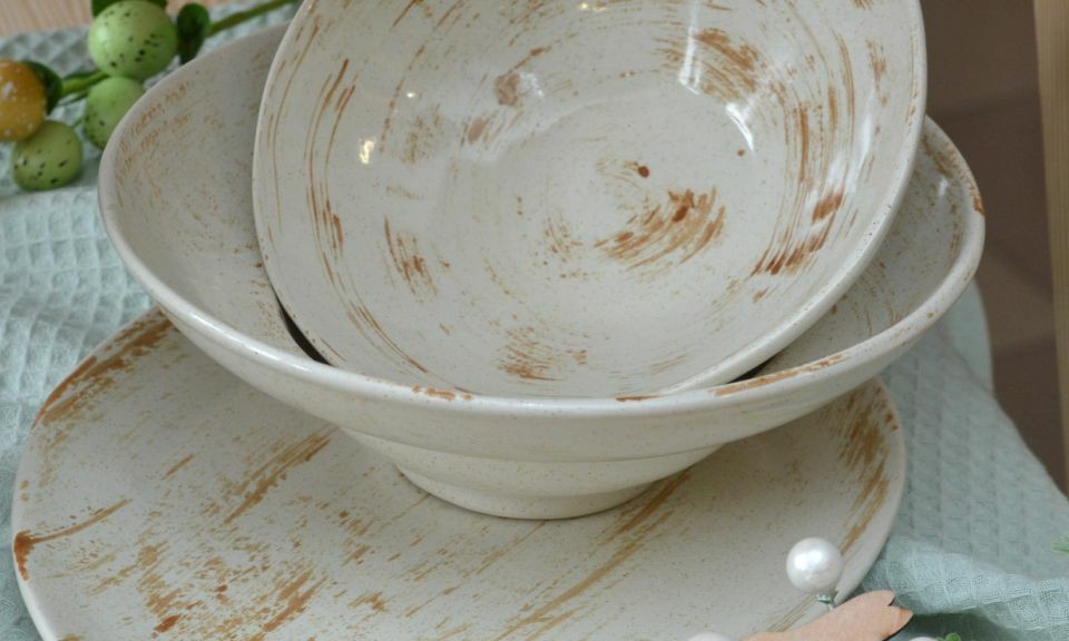 Ceramic bowls in pastel tones on a wooden surface table, next to decorative elements and a branch.